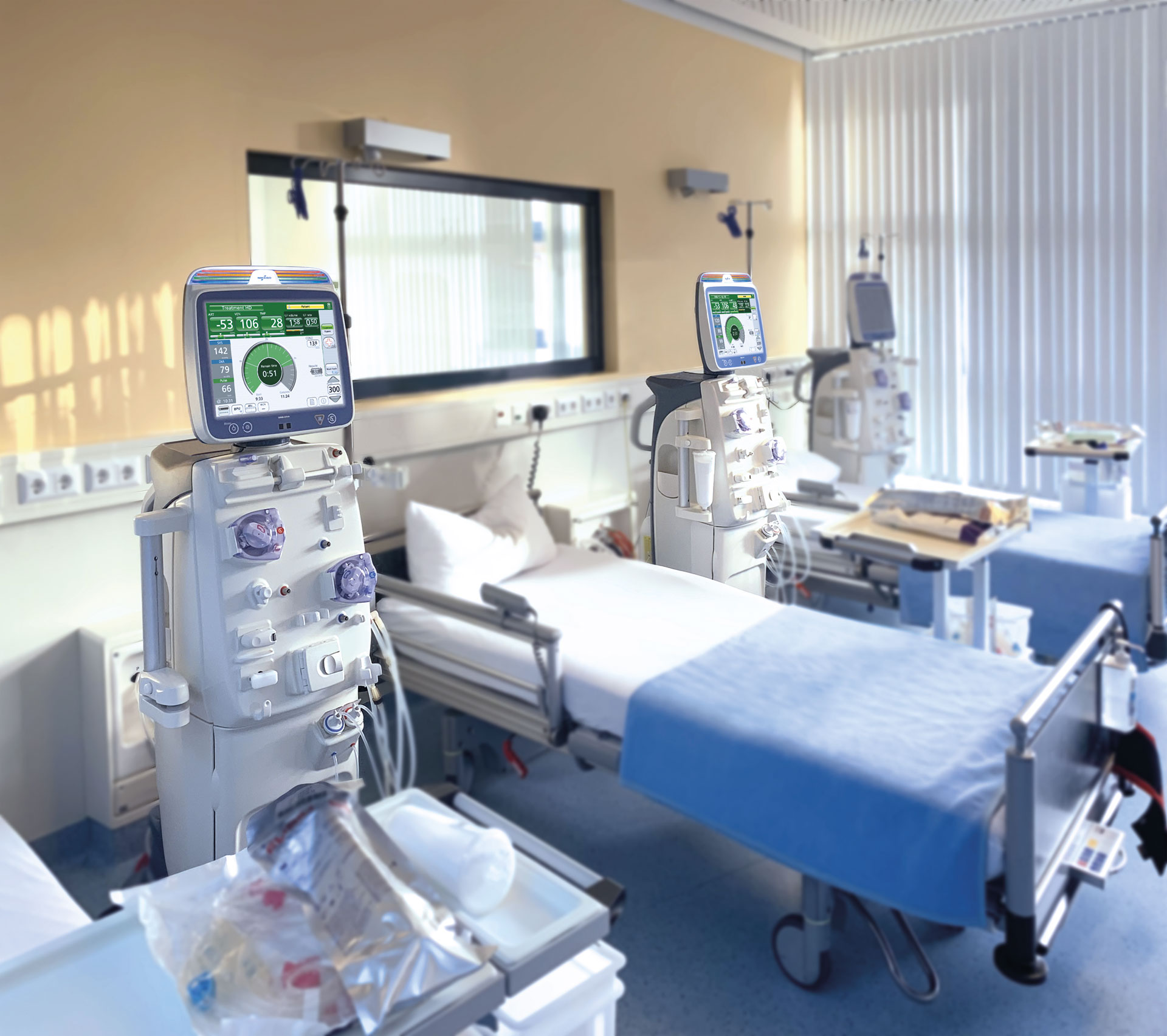 Behandlungsraum mit mehreren Dialysegeräten neben Patientenliegen, ausgestattet mit Monitoren, Schläuchen und medizinischem Zubehör.